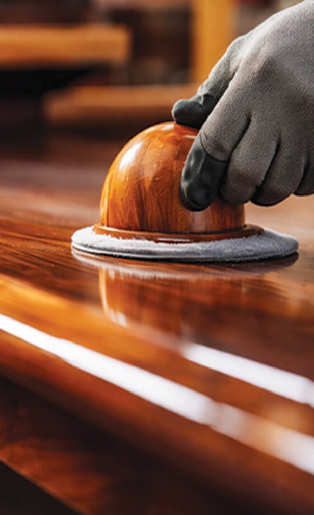 A gloved hand polishing a high-gloss timber surface
