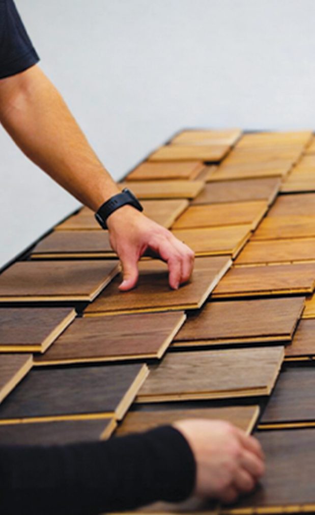 Hands laying out timber veneer samples across a workbench