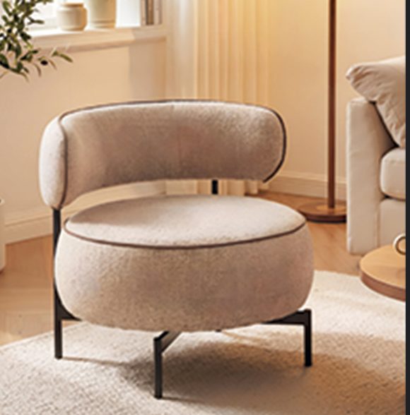 Curved boucle armchair on thin black legs in a sunlit room