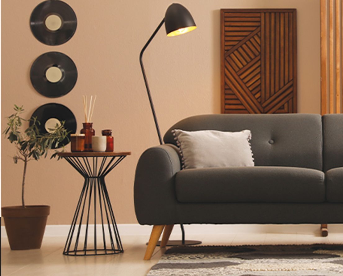 Dark grey sofa with a wire side table, floor lamp and wooden wall art